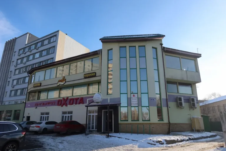 Фасад здания клуба "Охота" в Харькове по улице Бриагады Хартия 56. Вывески на украинском языке "Бильярд Охота" и "Караоке". Внешний вид "Охота" с элементами архитектуры и зимним пейзажем.